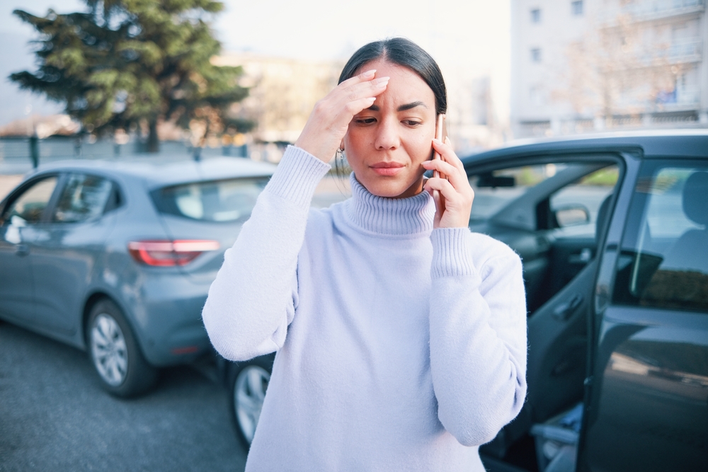 Woman calling insurance assistance after car accident
